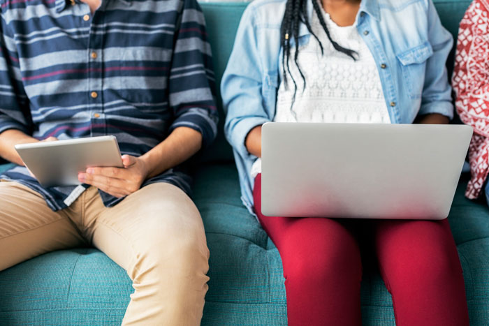 Millennials with tech devices in front of them on a blue bench