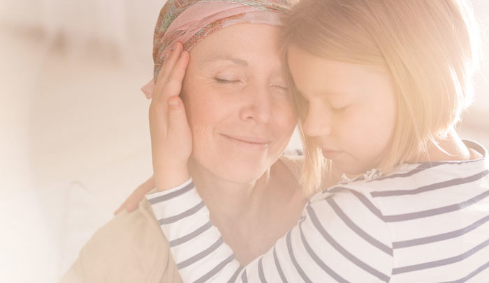 mother with breast cancer smiling and hugging her young daughter