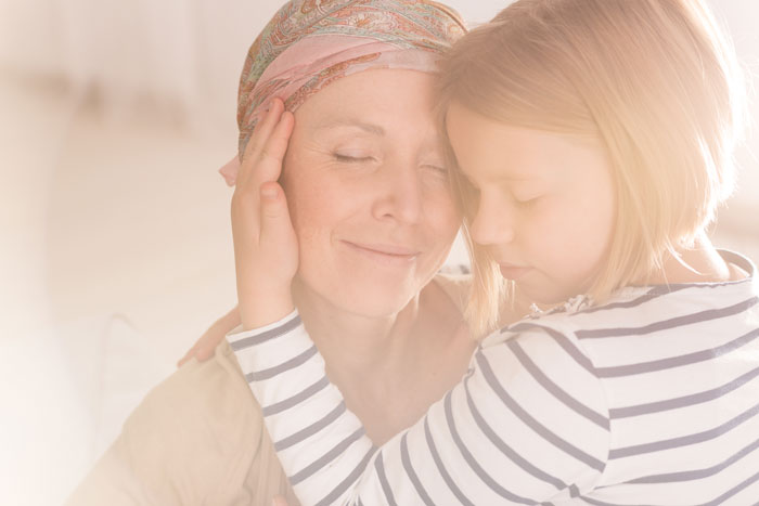 mother with breast cancer smiling and hugging her young daughter