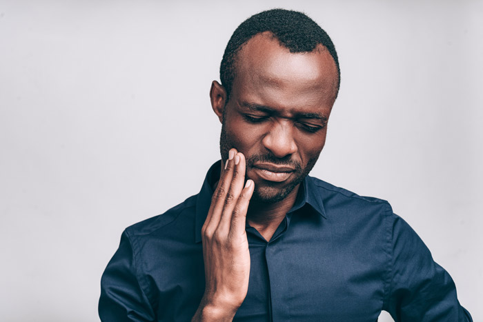 professional african american holding jaw experiencing dental pain