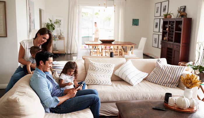 happy family on couch browsing health insurance options on tablet