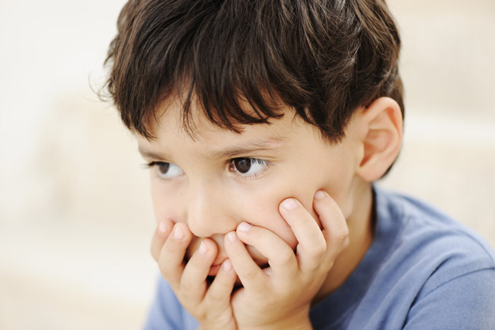 young boy scared with hands cupping his mouth